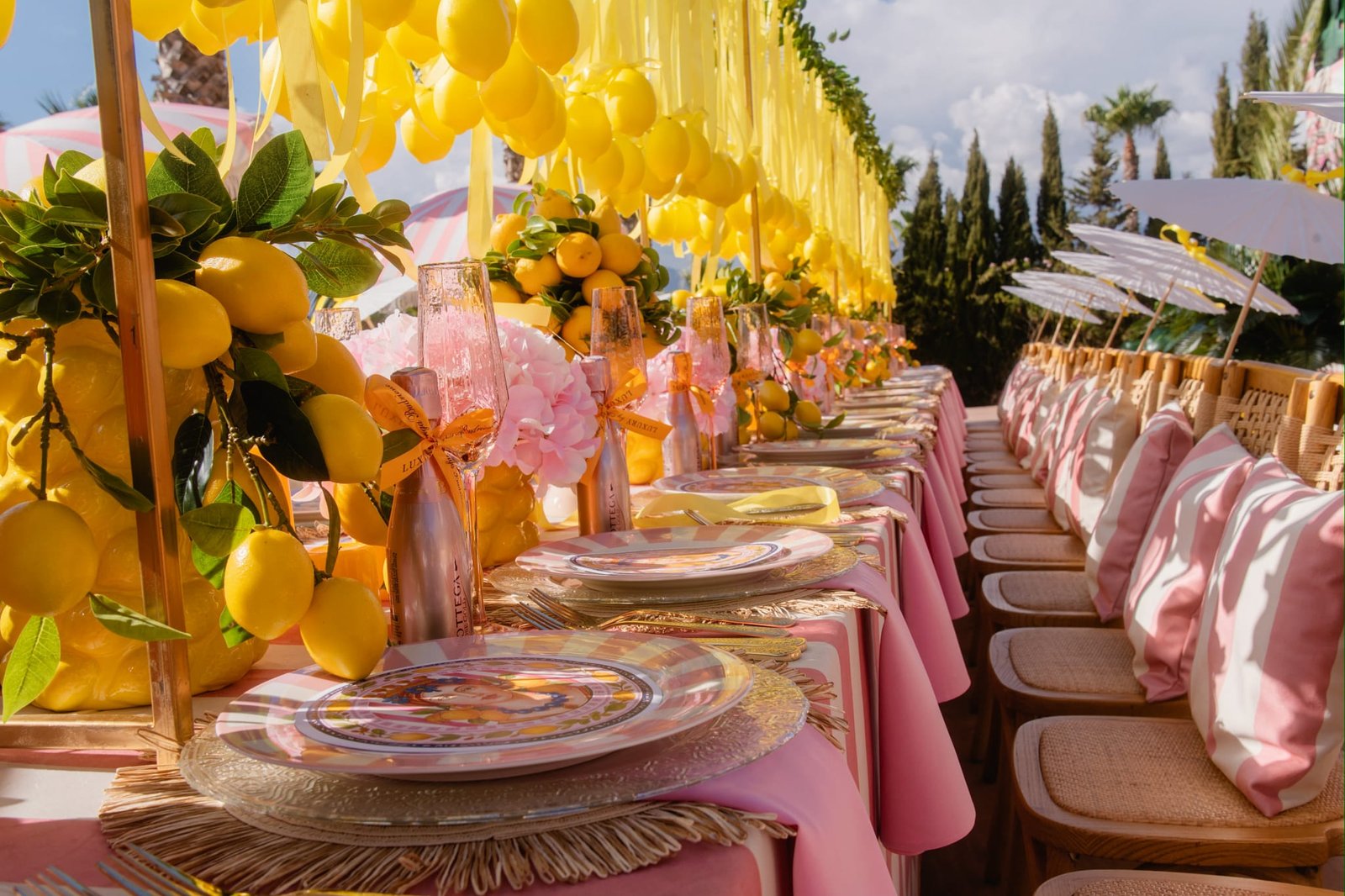 Long reception table styled with hanging lemon garlands and pink ribbon canopy