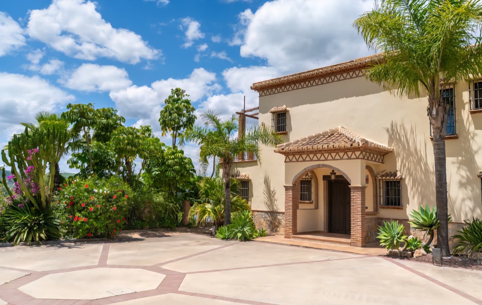 Brick-arched villa entrance with tiled canopy and octagonal paved courtyard